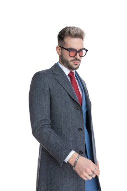 Dramatik iş adamı beyaz arka planda aşağı bakıyor ve güneş gözlüğü takıyor.