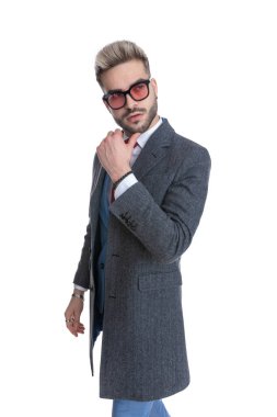 Yakışıklı iş adamı çenesini kaşıyor, başka tarafa bakıyor ve beyaz arka planda yürüyor.