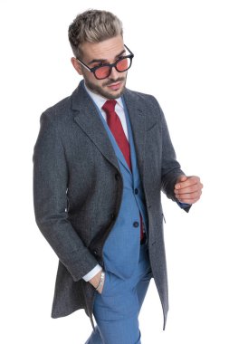 Yakışıklı iş adamı elini cebine atmış ve havalı güneş gözlüğü takıyor.