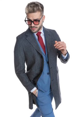 Bir eli cebinde ve güneş gözlüğü takan seksi iş adamı pozu