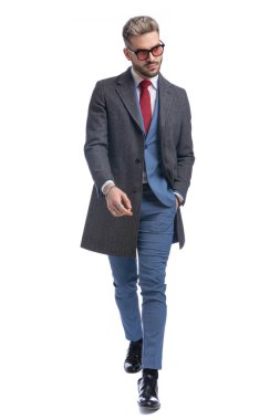 Zarif takım elbiseli ve uzun ceketli yakışıklı sakallı adam. Stüdyoda beyaz arka planda el ele yürüyordu.