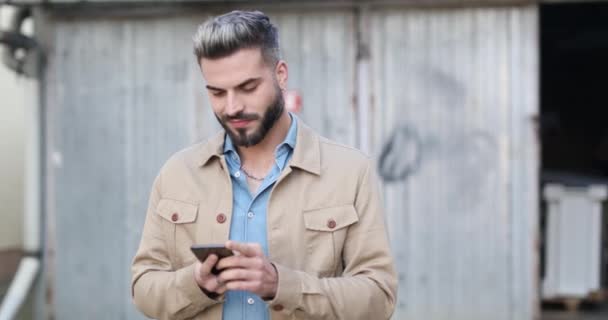 Nieogolony Facet Trzymający Telefon Czytający Wiadomości Uśmiechający Się Śmiejący Podnoszący — Wideo stockowe