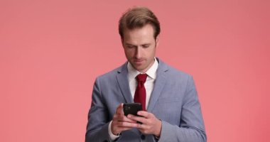 Gülümseyen sakallı iş adamı telefonda konuşuyor, gülüyor ve stüdyoda pembe arka planda iyi hissediyor.