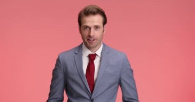 Hevesli iş adamı iyi haberler duyuyor, neşeli hissediyor ve alkışlıyor, parmaklarıyla işaret ediyor ve stüdyoda pembe arka planda güzel bir jest yapıyor.