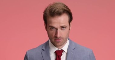 Stüdyoda pembe arka planda dururken takım elbiseli sıkkın işadamı esniyor, alkışlıyor ve ilgisini kaybediyor.