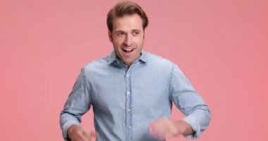 Havada yumruklar tutan, zaferi kutlayan, stüdyoda pembe arka planda neşeli çığlıklar atan heyecanlı, sıradan bir genç adam.