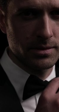 Çekici bir mankenin papyonunu düzelttiği ve kameraya yakından gülümsediği dikey bir video.