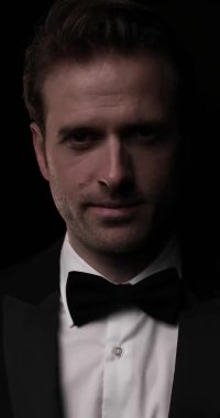 Koyu arkaplanda kameraya gülümseyen zarif bir iş adamının dikey videosu.