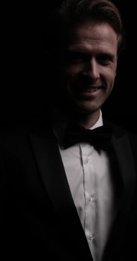 Kameraya gülümseyen yakışıklı bir iş adamının smokinini ve papyonunu tamir edip sonra da ayrıldığı dikey bir video.