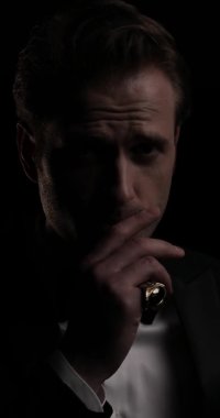 Yakışıklı bir iş adamının yüzüne dokunduğu, yüzük taktığı ve arka planda papyonunu düzelttiği dikey bir video.