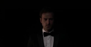 Karanlıktan gelen gizemli iş adamı papyonunu düzeltiyor, gülümsüyor ve gidiyor.