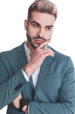 Tıraş olmamış çekici bir adam kollarını kavuşturuyor, yan yana durup el ele tutuşuyor ve stüdyoda beyaz arka planı düşünüyor.