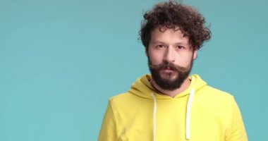 Sarı kapüşonlu sakallı hippi. Düşünüyor, komik suratlar yapıyor, bipolar oluyor, ağlıyor ve üzülüyor, kendini cesaretlendiriyor ve stüdyoda mavi arka planda gülümsüyor.