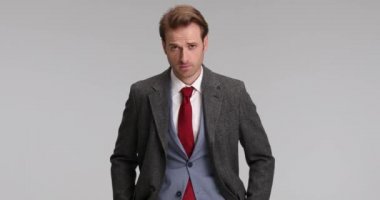 Yakışıklı iş adamı ellerini cebinden çıkarıyor, ceketini kapatıyor, kollarını kavuşturuyor ve kameraya gülümsüyor.