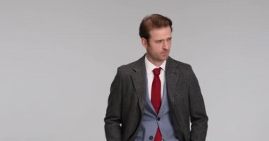 Genç yakışıklı işadamı ellerini cebine sokuyor, tavırlarıyla poz veriyor, ceketini kapatıyor, kameraya gülümsüyor ve sonra gidiyor.