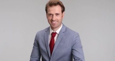 Mutlu iş adamı kollarını kavuşturur, çenesine dokunur, şehvetli bakışlar atar ve poz verir.