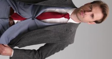 Avuçlarını ovuşturan, ellerini cebine sokan, çenesine dokunan kravatını düzelten ve oradan ayrılan seksi bir işadamının olduğu dikey bir video.