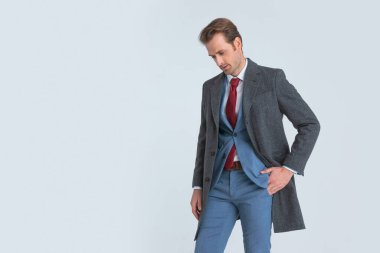 Dramatik iş adamı bir elini cebine sokup kravatlı bir takım elbise giyer.