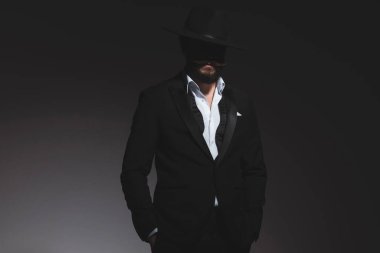 Yakışıklı, gizemli iş adamı elleri ceplerinde poz veriyor ve papyonunu takmış.