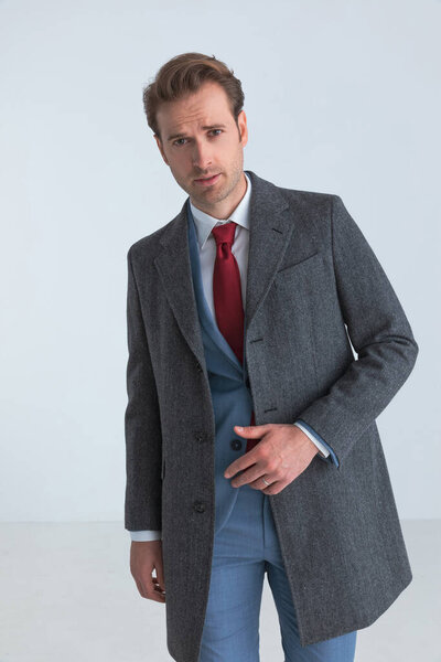 сексуальный бизнесмен позирует в элегантном костюме с галстуком и пальто над ним
