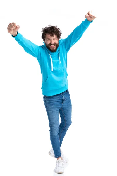 兴奋的未剃光头发的男人 身穿蓝色运动衫 手挽手在空中 一边欢庆胜利 一边在工作室的白色背景上独立行走 — 图库照片