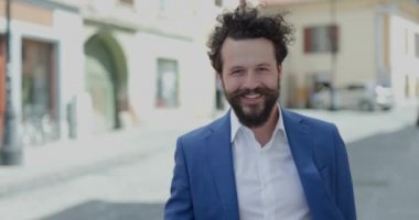 Romanya 'nın eski bir şehrinde ayakta dikilen ve poz veren, kahve içen ve gülümseyen seksi, zeki bir adam.