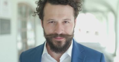 Bıyıklı, kıvırcık saçlı, şehir arka planında poz veren çekici, genç bir manken.