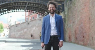 Romanya 'dan gelen havalı ortaçağ şehir geçmişi önünde poz veren ve mutlu gülümseyen genç turist.