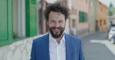 Uzun bıyıklı, sakallı, poz veren ve şehrin arka planında gülümseyen seksi bir genç portresi.