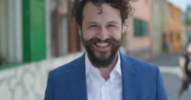 Yakışıklı genç adam gülüyor, yan tarafa bakıyor ve şaşırmış bir yüz ifadesi takınıyor arkasında ortaçağdan kalma bir şehir geçmişi var.