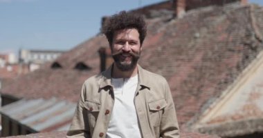 Genç, yakışıklı, sıradan bir adam kameraya gülümsüyor ve dışarıda mutlu.