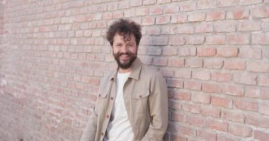 Yakışıklı, sıradan bir adam duvara yaslanmış ve kameraya gülümsüyor.