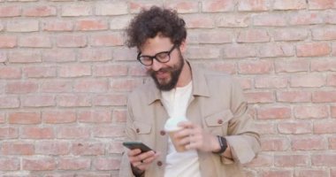 Seksi, sıradan bir adam kahvesini içiyor, telefonuna mesaj atıyor, gözlük takıyor ve duvara yaslanıyor.