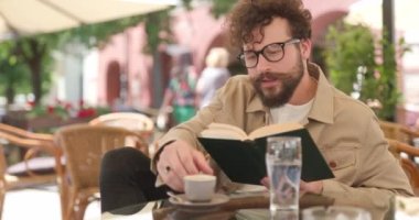 Çekici, sıradan bir adam kahvesini alıp içiyor, kitap okuyor, gözlük takıyor, gülümsüyor ve terasta oturuyor.