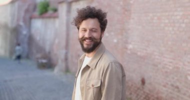 Sıradan bir adamın kameraya dönüp dışarıda gülümsemesinin yan görüntüsü.