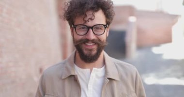 Eski kasabada elinde bir fincan kahveyle, gözlüklü ve gülümseyen seksi sıradan bir adam.