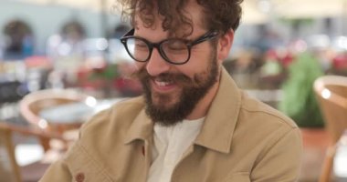 Yakışıklı, sıradan bir adam terasta kahve içiyor.