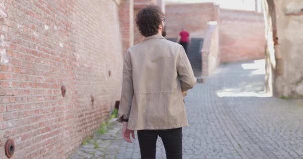 シビウの旧市街を歩き回って挨拶をする気軽な男の後ろ姿 — ストック動画