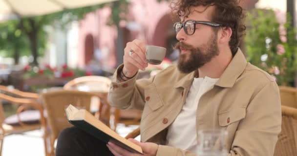Lässiger Junger Mann Der Seinen Kaffee Genießt Sein Buch Mit — Stockvideo