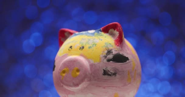 Banco Piggy Colorido Girando Lado Para Outro Contra Fundo Azul — Vídeo de Stock