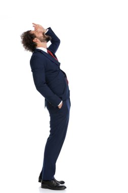 Yakışıklı bir iş adamının, yukarıdaki daha iyi bir şeyi görebilmek için gözlerini güneş ışığından koruması. 