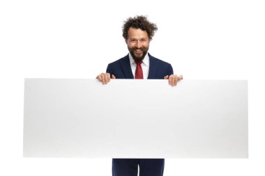 Yakışıklı iş adamı kameraya bakıyor, elinde boş bir ilan panosu var ve gülümsüyor.