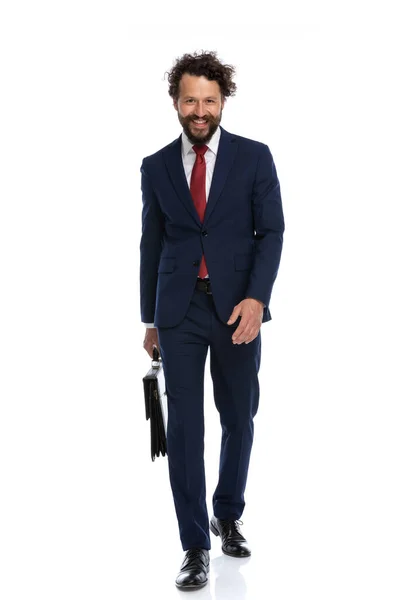 セクシーなビジネスマンがカメラの方へ歩いて笑顔で白い背景にブリーフケースを持って — ストック写真