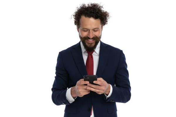 Junger Geschäftsmann Blickt Auf Sein Handy Und Lächelt Vor Weißem — Stockfoto