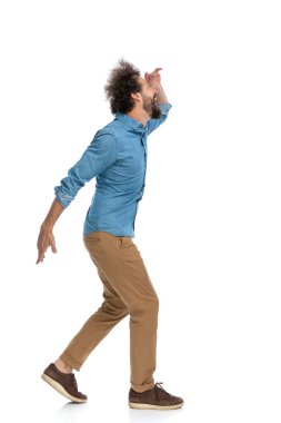 Yakışıklı, sıradan bir adamın yürümesi, gözlerini koruması ve beyaz arka plana bakması.