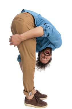 Öne eğilip bacaklarını beyaz arka plana yaslayan sıradan bir adamın yan görüntüsü.