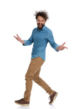 Sıradan bir genç adamın kollarını açıp beyaz arka planda gülümsemesinin yan görüntüsü.