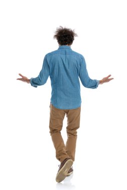 Kolları beyaz stüdyo arka planına karşı açık yürüyen sıradan bir adamın arkadan görünüşü.