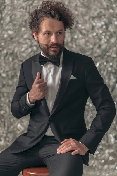 Sexy Young Man Elegant Tuxedo Looking Side Fixing Jacket Sitting — Stock Photo, Image