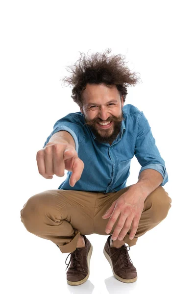 Handsome Casual Man Squatting Resting His Hand Pointing Camera Excitement — Stock Photo, Image